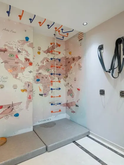 We transformed a corner of this home into a fun and active play zone for the kids. The wall features a world map mural and a climbing ladder with safety mats below, encouraging adventure and physical activity in a safe, indoor environment.