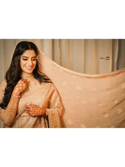 A wide-format shot that lets the bride's smile and the delicate fabric of her dupatta shine. This is a simple yet incredibly elegant bridal portrait.