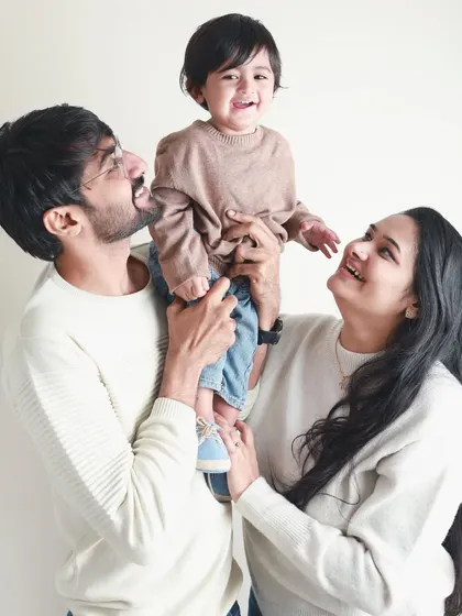 Looking up with love. This family portrait is all about shared joy, with the parents' happy faces reflecting the delight of their child.