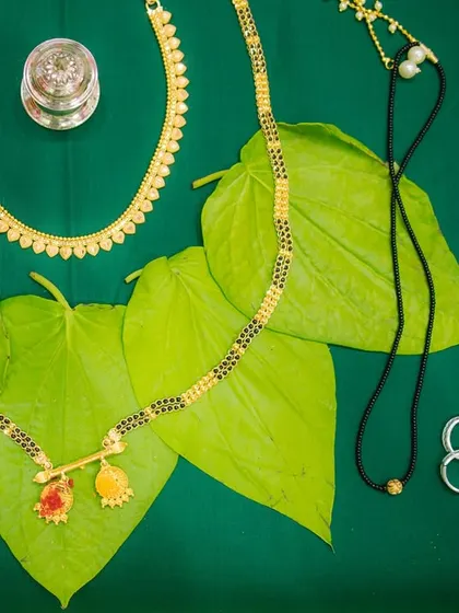 A detail shot of the sacred Mangalsutra and other traditional jewelry laid out on betel leaves. We believe in capturing these symbolic details that are central to the wedding ceremony.