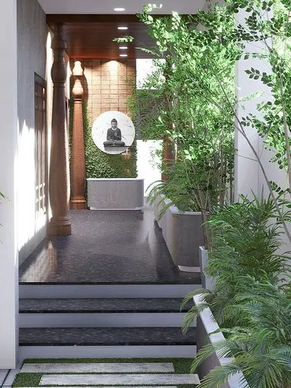 A view from the walkway leading towards the entrance, lined with lush greenery in concrete planters.