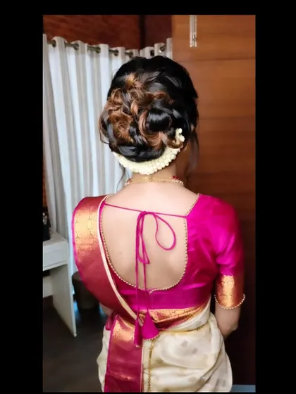 A modern, textured bun with highlights, adorned with a simple jasmine gajra. This style is great for adding dimension.