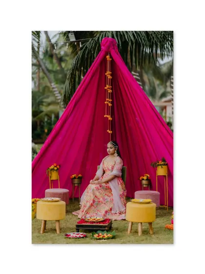 The bride looking serene and beautiful at her Mehendi ceremony, seated in a specially designed space with bright pink drapes.