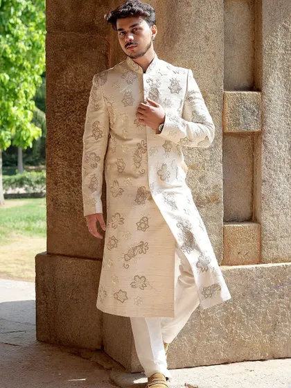 The side-split detail of this ivory sherwani allows for ease of movement while maintaining a regal silhouette. The intricate embroidery is visible from every angle, ensuring a stunning appearance.