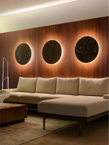 The family room, which we call the 'Solar Eclipse' room, features a fluted wood wall with three back-lit stone discs. It's a dramatic and cozy space for lounging.