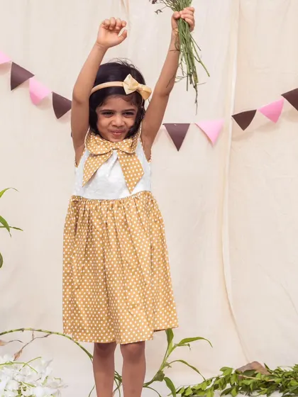 Reaching for the stars in this adorable mustard yellow polka dot dress. The oversized bow collar adds a touch of whimsy to this playful outfit.