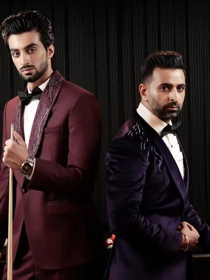 A powerful duo, featuring our maroon tuxedo with embroidered lapels and our purple velvet tuxedo with shoulder details. Both are perfect examples of our commitment to creating unique, handcrafted formal wear.