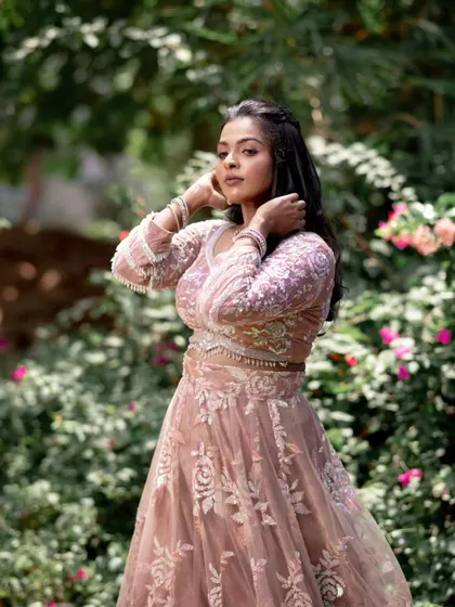 A model posing in a pink lehenga, with a focus on her beautiful, flowing hair and subtle makeup.