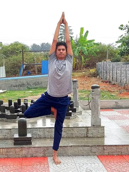 Vrikshasana, or Tree Pose, performed here near a representation of the twelve Jyotirlingas. This asana cultivates balance and stability, mirroring the unwavering presence of the divine.