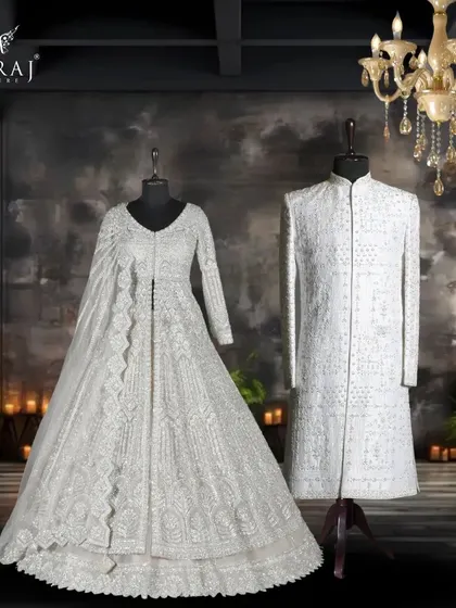 This pairing showcases timeless elegance in shades of grey and white. The groom's classic off-white silk sherwani with Persian embellishments complements the bride's light grey Indo-Western gown and designer veil.