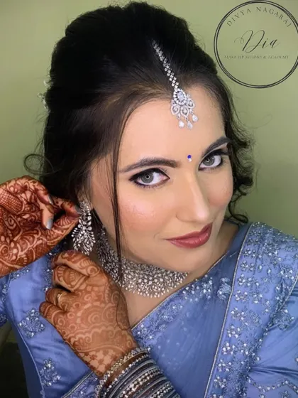 This candid getting-ready shot shows the final touches being put on the bride's reception look. The combination of the intricate henna, sparkling diamond earrings, and flawless makeup creates a picture of pure grace.