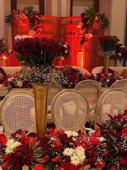 A luxurious seating arrangement for a traditional wedding, surrounded by an abundance of red flowers. The design combines classic furniture with rich floral decor to create a space that feels both grand and intimate.