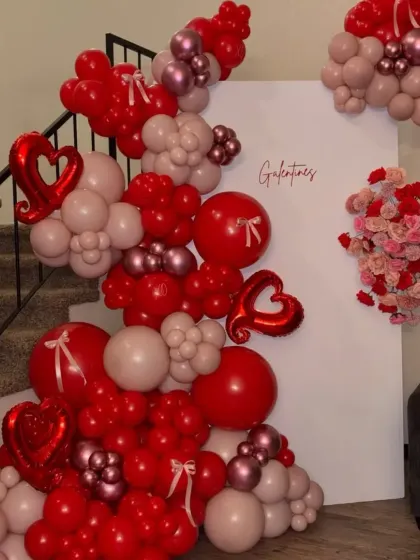 Decorating a staircase with a balloon garland is a great way to welcome guests. This Valentine's arrangement uses shades of red and pink with heart-shaped foil balloons to set a festive mood.