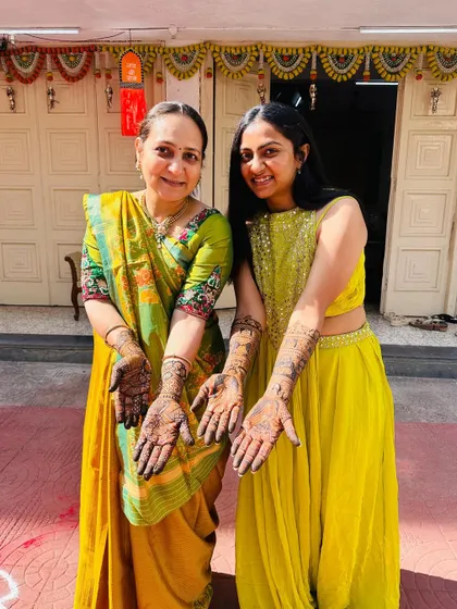A beautiful moment between a mother and daughter, both adorned with mehendi for the wedding. It's a celebration for the whole family.