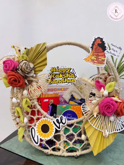 A beautifully decorated Rakhi hamper in a jute net basket. Adorned with handmade flowers and fun stickers, it’s a delightful surprise for your brother.