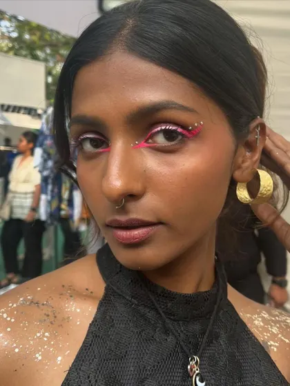 A bold festival look with a neon pink graphic liner, rhinestones, and body glitter. I love creating these vibrant and expressive looks for events like the Under 25 Summit.