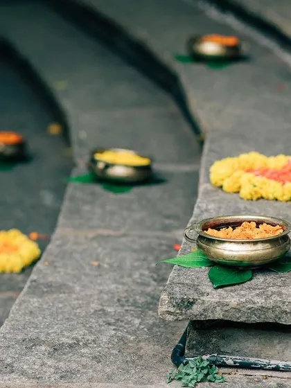 Small brass bowls filled with colorful flower petals are placed along the stone steps, a simple yet beautiful detail.