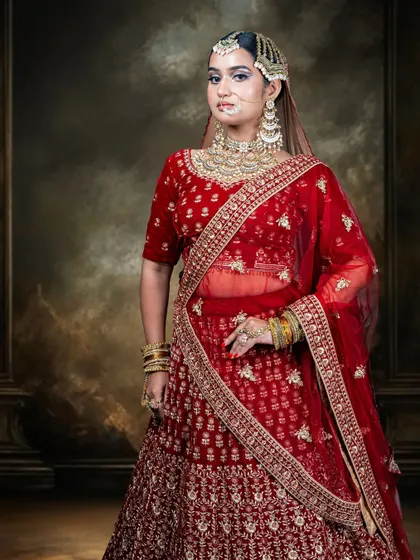 The rich red fabric and detailed gold embroidery of this bridal lehenga create a look of pure opulence. It's a perfect choice for the main wedding ceremony, ensuring you look every bit the traditional, radiant bride.