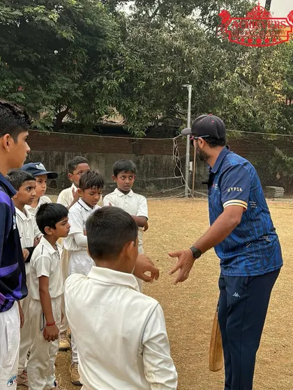 A coach having a discussion with a group of young players on the field. We teach game awareness and strategy alongside physical skills.