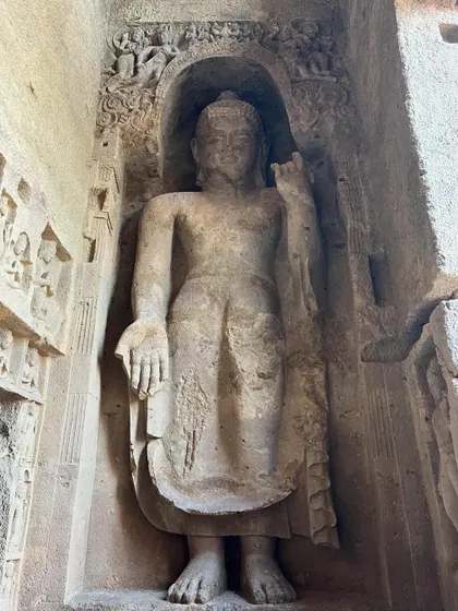 Another large standing Buddha sculpture carved into an alcove within the Kanheri cave complex.