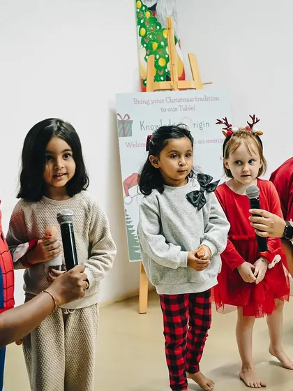 A group of girls holds microphones, preparing to sing for their parents. Performing on stage is a huge confidence booster for young children.