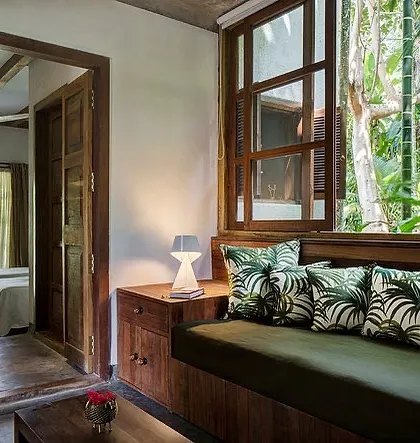 A comfortable daybed in the Garden Room lobby, looking out a large window into the lush greenery.