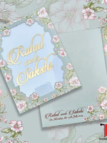 A soft sage green laser-cut invitation with a delicate floral border and personalized gold acrylic names for a sophisticated touch.