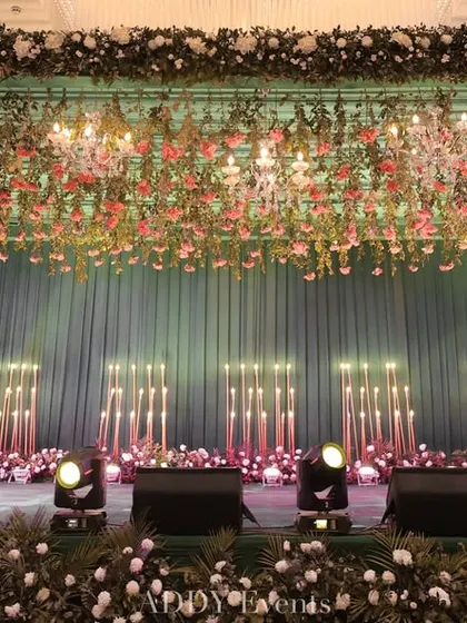 A clear, eye-level view of the teal and floral stage. This shot provides a good look at the hanging floral installation and the arrangement of lights, demonstrating the rich textures and colors we use in our designs.