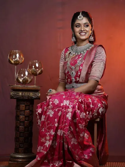 This silver-finish AD diamond set offers a sophisticated and modern bridal or reception look. The intricate design of the necklace and matching belt (vaddanam) pairs beautifully with this floral pink saree.