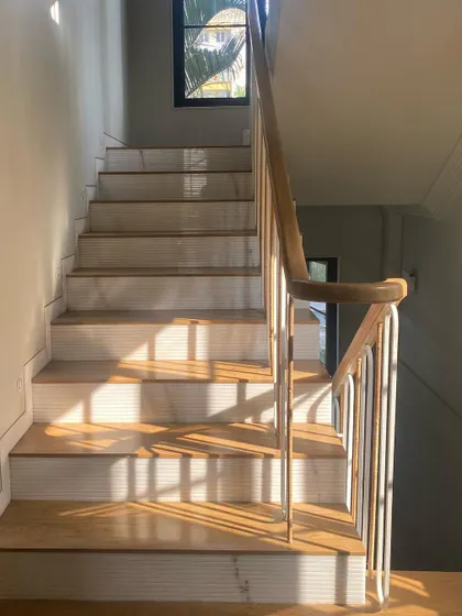 Sunlight streams across the marble and wood staircase at Summer Haus, highlighting the beautiful materials and craftsmanship.