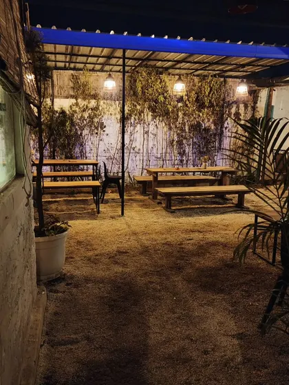 The same cafe space at night, where warm industrial lighting creates an intimate and magical atmosphere amidst the greenery.