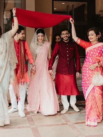 The bride's grand entrance, escorted by her brothers under a red dupatta, a vibrant and emotional start to the ceremony.