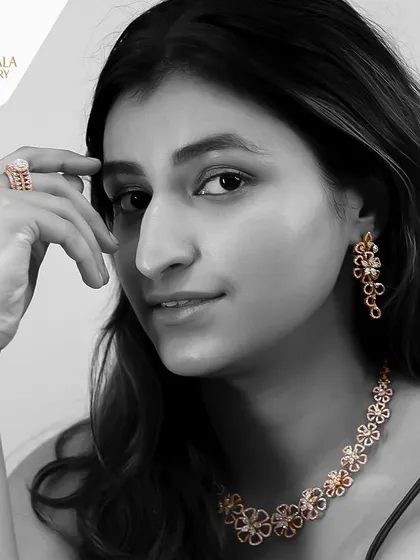 A black and white image with a color pop on a floral diamond set. This artistic shot highlights the timeless design and intricate details of the necklace, earrings, and ring.