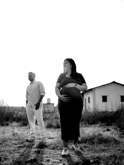 A strong black and white portrait of the couple in a field. They stand apart but are connected by their shared gaze towards the future, with the baby bump as the center of their world.