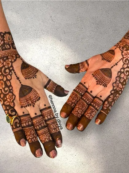 This cutwork bell mehendi is a unique and eye-catching design. The negative space around the jhumkas makes them pop, creating a three-dimensional effect.
