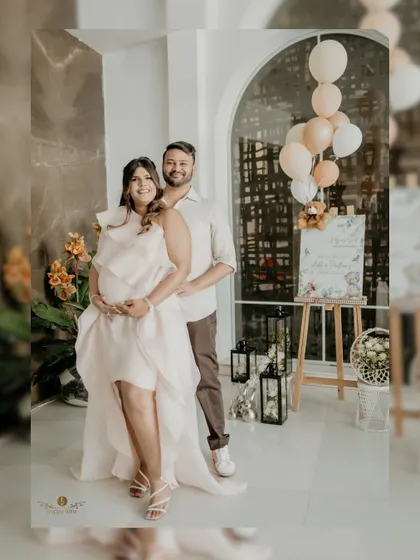 A lovely portrait of the expecting couple at their baby shower. They stand together by the welcome sign, their smiles full of love and anticipation.