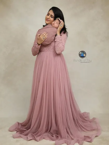 A mother holds her sleeping newborn, both dressed in shades of pink. This timeless studio portrait beautifully captures the serenity of early motherhood.