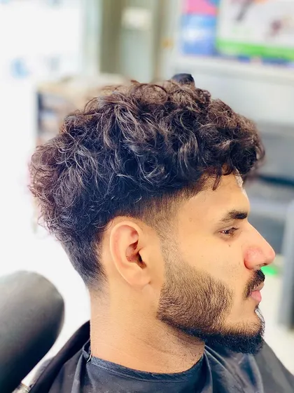 Working with curly hair requires a different technique. I created a taper fade that controls the sides while leaving natural texture and volume on top, complemented by a clean beard line up.