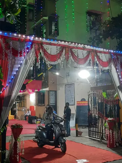 An entrance gate for a night event, decorated with red and white drapes and festive string lights.