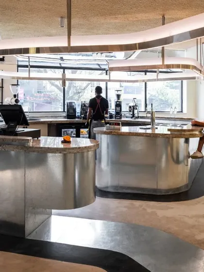 The sweeping curves of the brew bar and the overhead lighting element create a sense of fluid movement throughout the cafe.