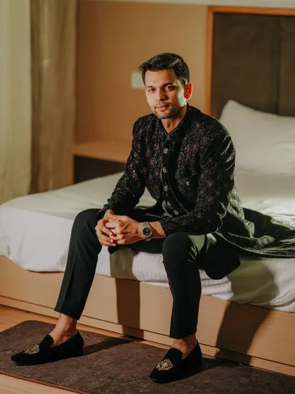 A stylish portrait of the groom sitting on a bed. The clean lighting and simple background create a modern and sophisticated look.