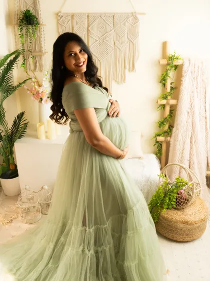 A smiling portrait in a lovely sage green gown. The natural light from the side creates a soft and flattering glow.