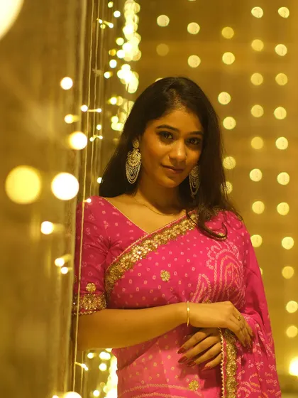 Framed by a curtain of festive lights, this portrait captures the magical glow of Dev Deepawali and the elegance of traditional Indian attire.