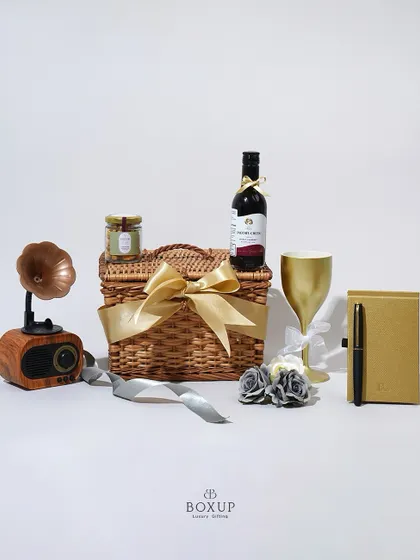 The "Vintage Dreams" hamper is a classic choice for Women's Day. It features a retro-style Bluetooth speaker, a non-alcoholic wine, a golden goblet, and a journal for the modern woman.