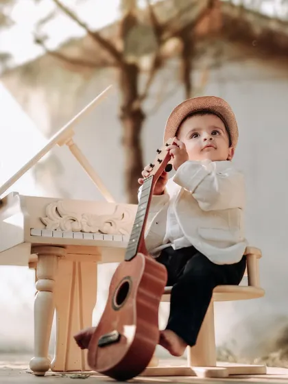 A little musician with his guitar. This creative setup with a miniature piano and guitar is perfect for capturing a child's budding love for music.