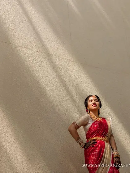 A confident and stylish bridal portrait. The bride strikes a pose against a simple wall, with dramatic shadows adding an artistic touch.