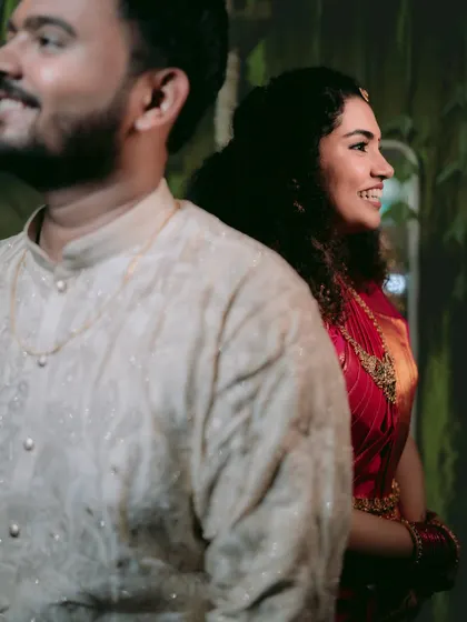 A candid, stolen moment between a South Indian couple, their smiles hinting at a shared secret.