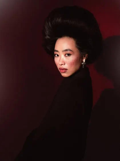 A dramatic and moody headshot with a voluminous hairstyle. The side lighting creates depth and shadow, perfect for a more theatrical or high-fashion look.
