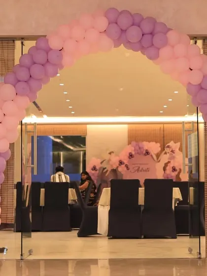 A simple U-shaped balloon arch in pastel pink and purple. This type of entrance decor is versatile and can be adapted to many different themes and color schemes.
