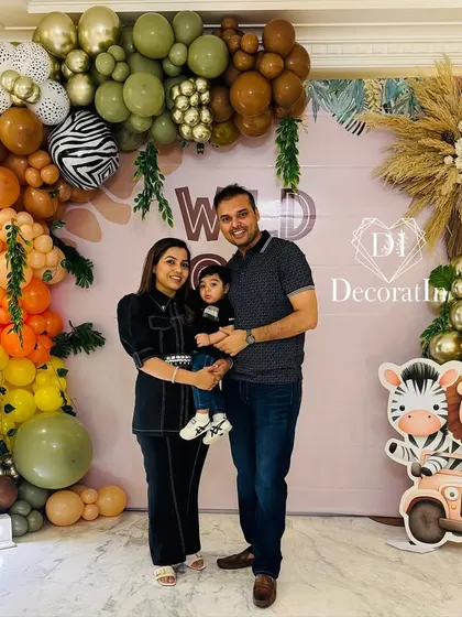 A full family portrait in front of the complete safari-themed backdrop, showcasing the balloon arch and cute animal props.